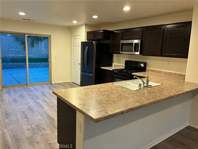 a kitchen with kitchen island granite countertop wooden cabinets a refrigerator and a sink