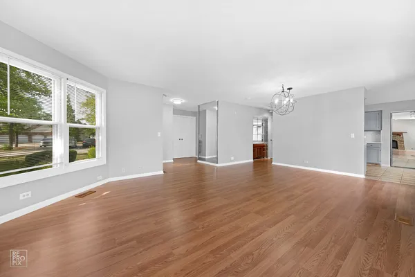 a view of empty room with wooden floor and windows