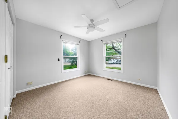 an empty room with windows and ceiling fan