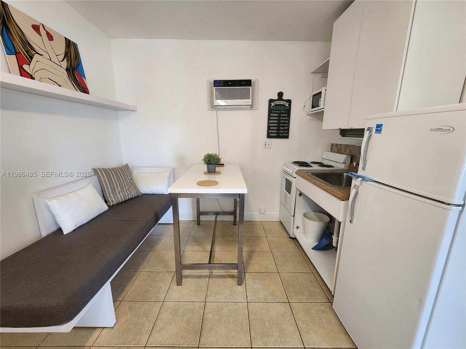 315 Walnut Street, Unit 2 Hollywood, FL 33019 - Photo 8 of 23 a white kitchen with a stove a refrigerator and a dining table