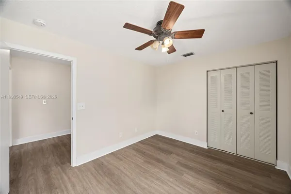 an empty room with wooden floor fan and windows