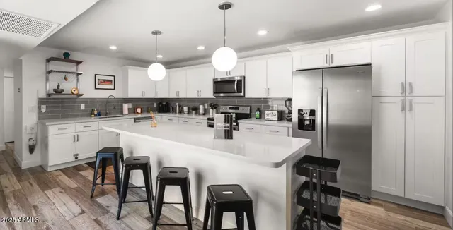 a kitchen with refrigerator a sink and chairs