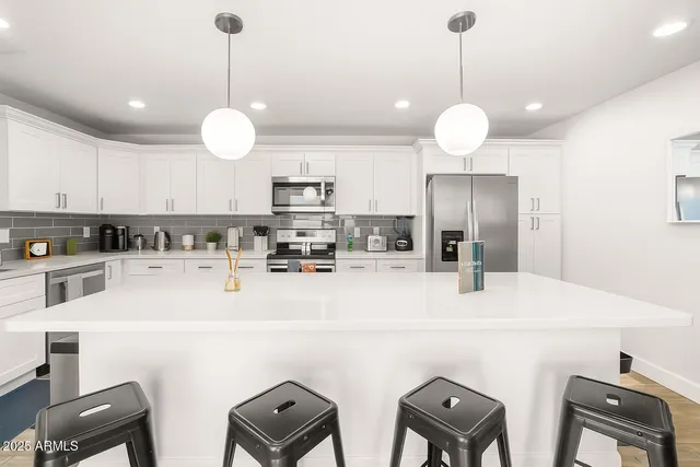 a kitchen with stainless steel appliances a refrigerator sink and chairs