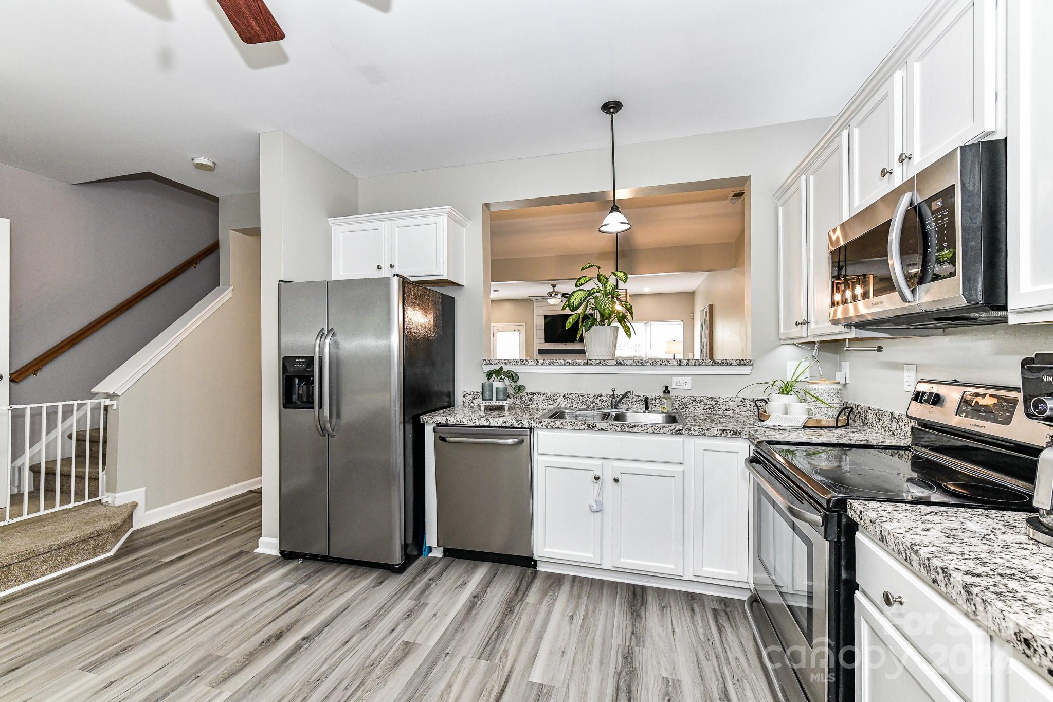 9665 Bailey Road Cornelius, NC 28031 - Photo 15 of 31 a kitchen with stainless steel appliances granite countertop a sink a stove a refrigerator cabinets and wooden floor