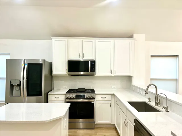 a kitchen with stainless steel appliances a stove a sink a microwave and refrigerator