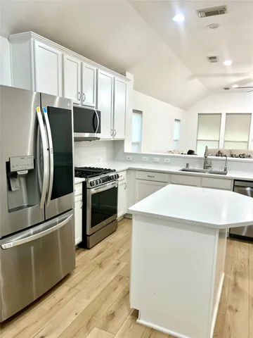 a kitchen with stainless steel appliances a stove a sink and a refrigerator