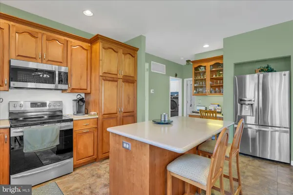 a kitchen with stainless steel appliances granite countertop a refrigerator a stove a sink a dining table and chairs