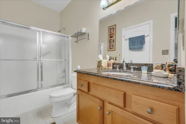 a bathroom with a granite countertop sink a toilet mirror and shower