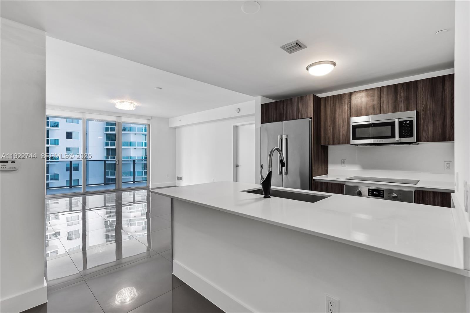 488 Northeast 18th Street, Unit 2311 Miami, FL 33132 - Photo 6 of 40 a kitchen with stainless steel appliances a sink and a refrigerator