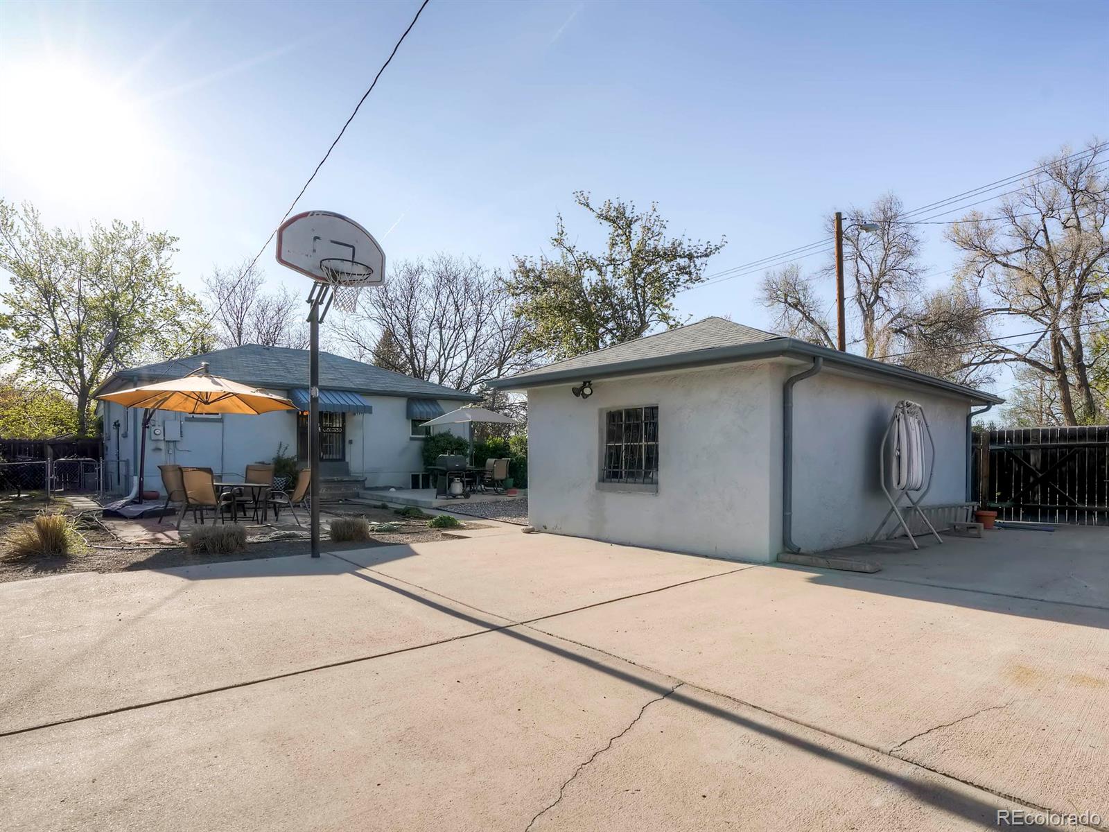 1370 Olive Street Denver, CO 80220 - Photo 23 of 27 a backyard of a house with table and chairs under an umbrella