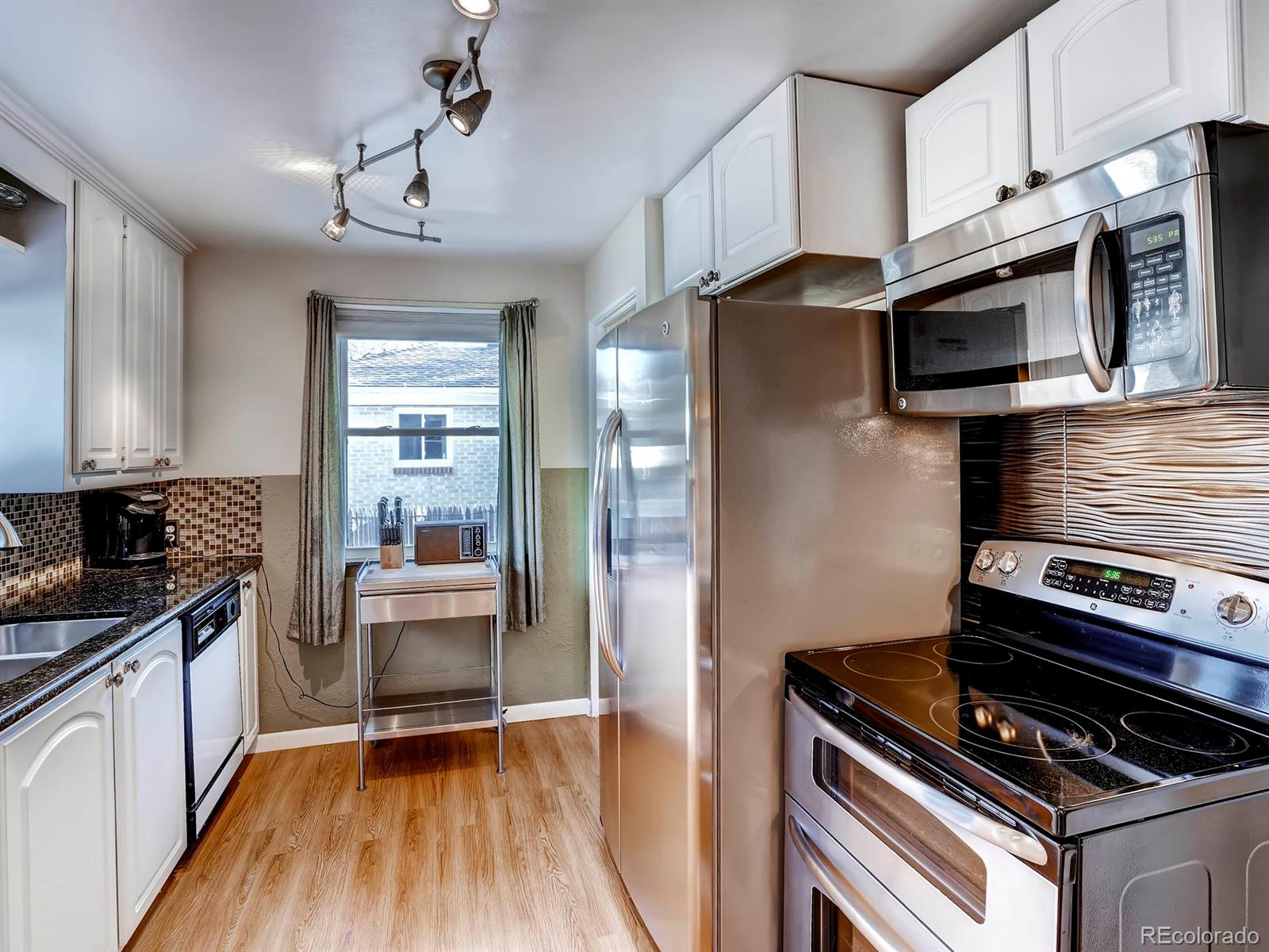 1370 Olive Street Denver, CO 80220 - Photo 8 of 27 a kitchen with stainless steel appliances granite countertop a stove and a refrigerator
