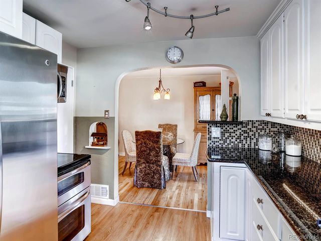 a kitchen with stainless steel appliances granite countertop a refrigerator a stove and a wooden floors