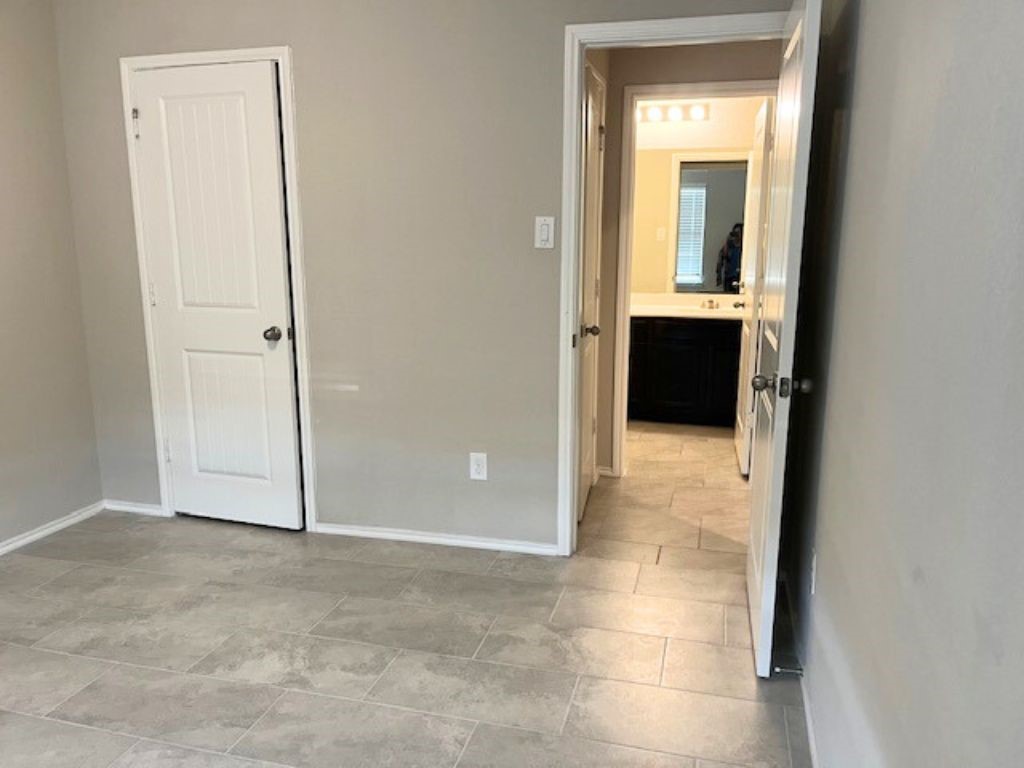 8310 Rose Petals Lane Rosharon, TX 77583 - Photo 19 of 43 Comfortable front bedroom located near the second bathroom, featuring tile flooring and convenient access to its own walk-in closet. The room offers a bright and functional space that can be used as a bedroom, guest room, or home office.