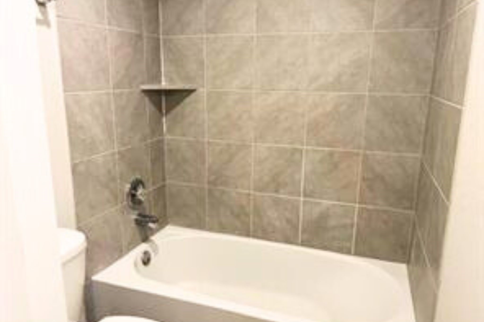 8310 Rose Petals Lane Rosharon, TX 77583 - Photo 25 of 43 Second bathroom tub and shower combination featuring tiled walls and a built-in shelf for convenience. The clean and functional design makes this bathroom ideal for everyday use by family members or guests.