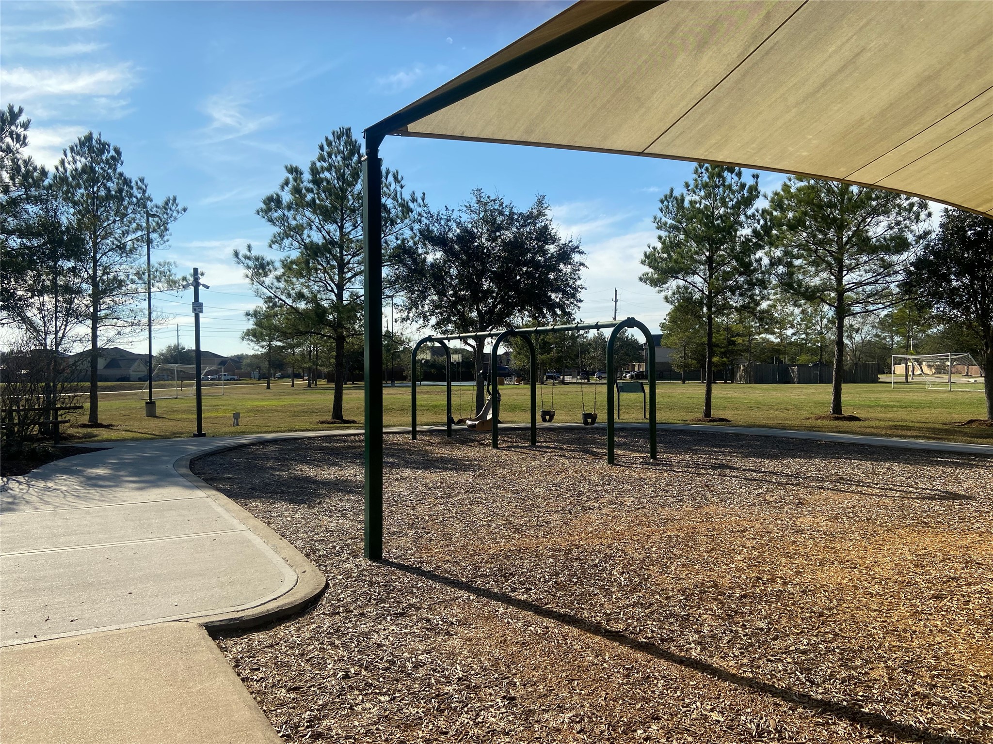 8310 Rose Petals Lane Rosharon, TX 77583 - Photo 40 of 43 Shaded community swing area in Southern Colony, featuring multiple swings beneath a large canopy for comfortable outdoor play. Located next to the neighborhood park and walking trails, this space offers a relaxing and family-friendly setting for residents to enjoy the outdoors