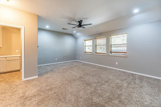 an empty room with windows and ceiling fan