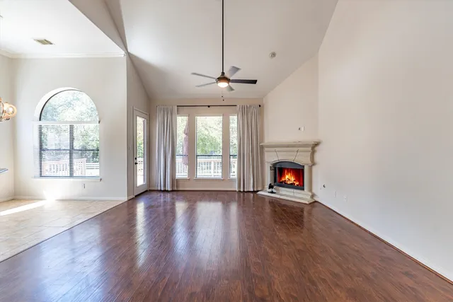 a view of an empty room with wooden floor fireplace and a window