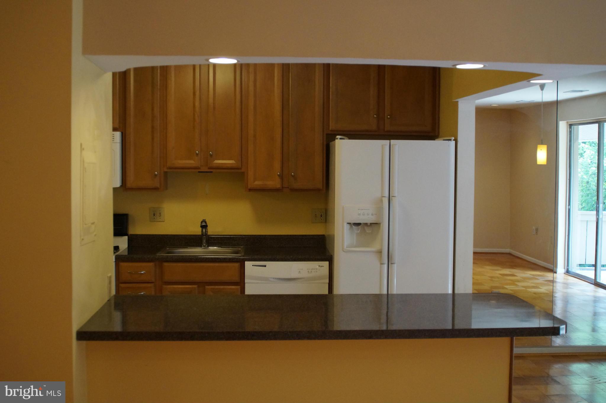109 Cross Keys Road, Unit R109F Baltimore, MD 21210 - Photo 5 of 13 a kitchen with kitchen island granite countertop wooden cabinets and refrigerator