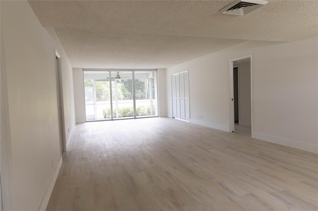 4007 North Cypress Drive, Unit 103 Pompano Beach, FL 33069 - Photo 2 of 25 an empty room with wooden floor and windows