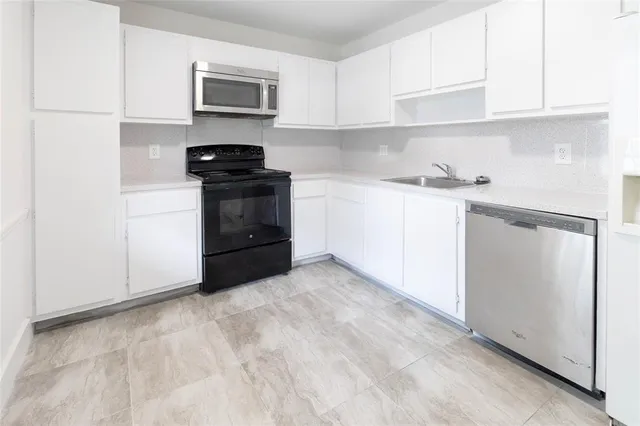 a kitchen with stainless steel appliances a stove and white cabinets