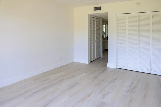 an empty room with wooden floor and closet