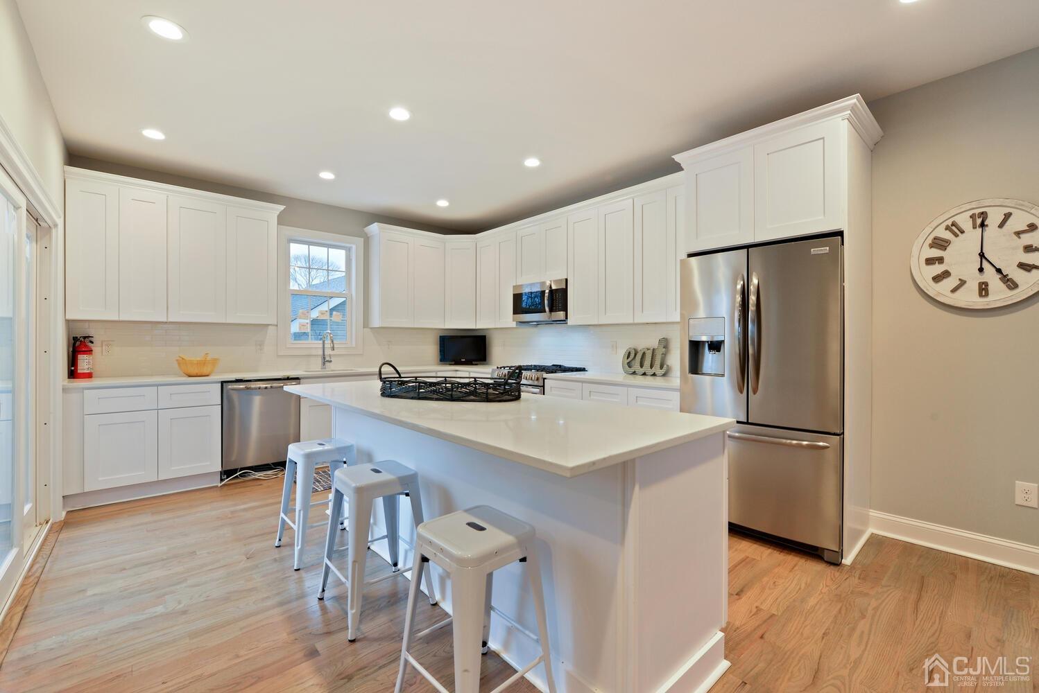 20 Sunset Drive Clark, NJ 07066 - Photo 15 of 32 a kitchen with a refrigerator a white stove top oven and white cabinets with wooden floor