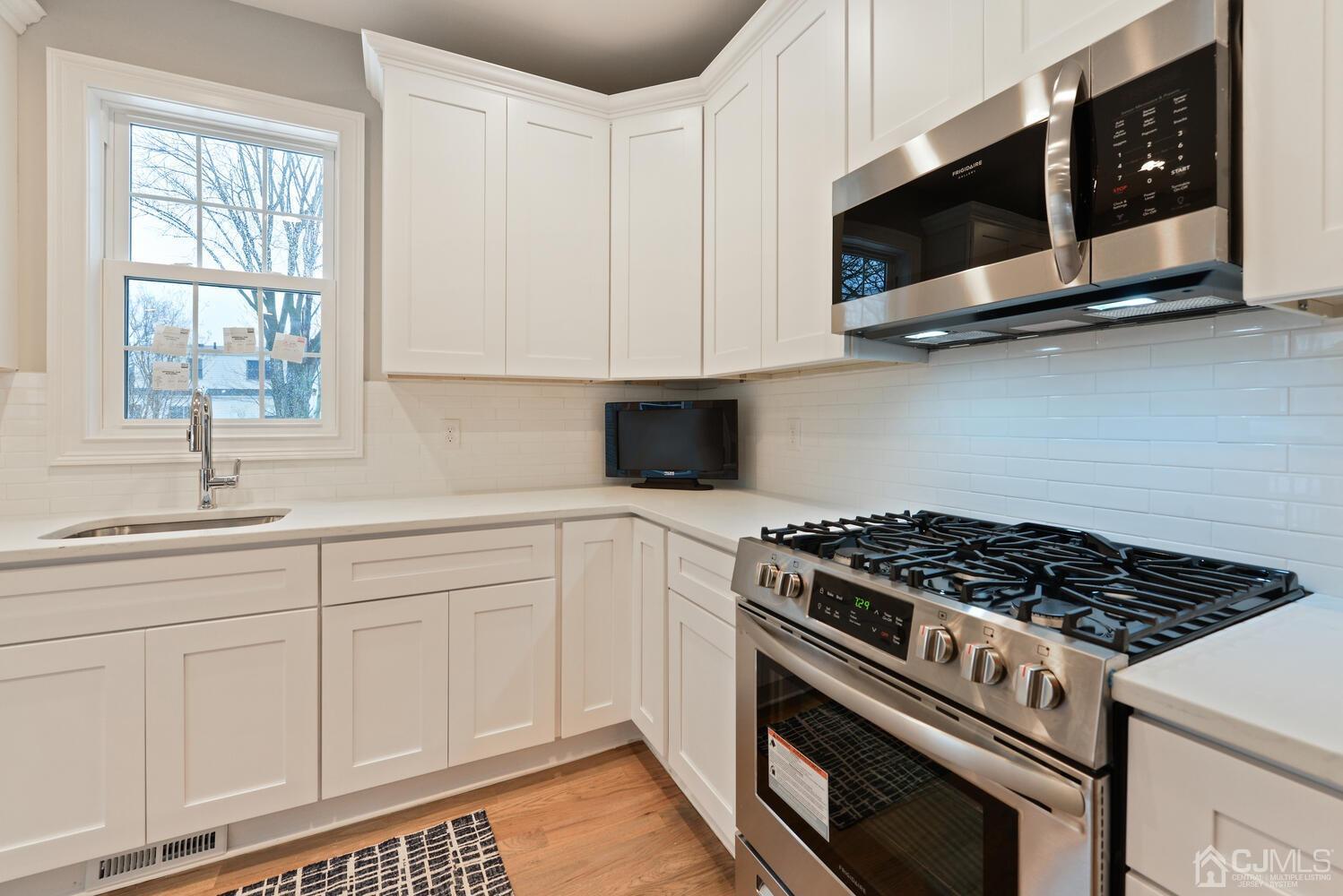 20 Sunset Drive Clark, NJ 07066 - Photo 5 of 32 a kitchen with stainless steel appliances white cabinets and a stove a oven with wooden floor