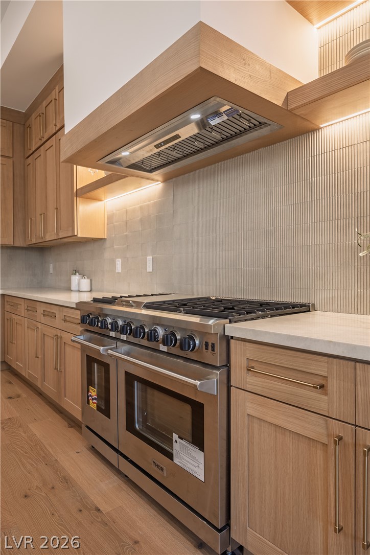 8800 Lusso Las Vegas, NV 89134 - Photo 34 of 85 Kitchen with double oven range, light wood-style floors, backsplash, light stone countertops, and light wood finish cabinetry