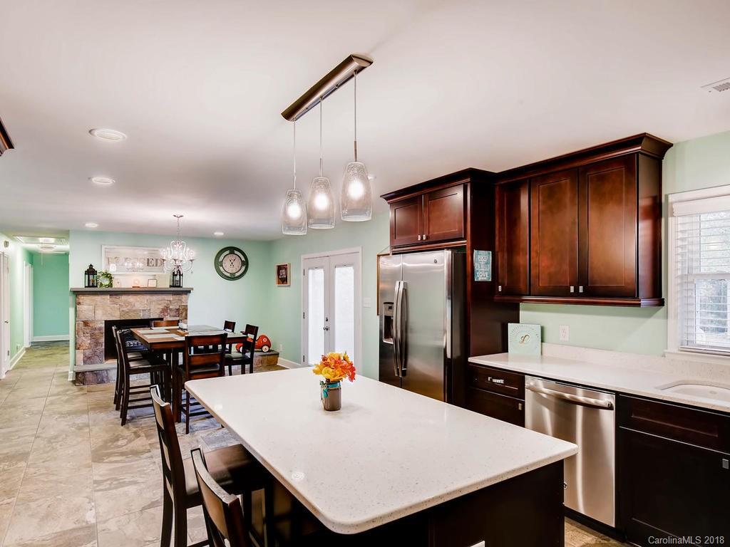 2411 Medlin Road Monroe, NC 28112 - Photo 12 of 27 a kitchen with stainless steel appliances kitchen island granite countertop a table chairs stove and refrigerator