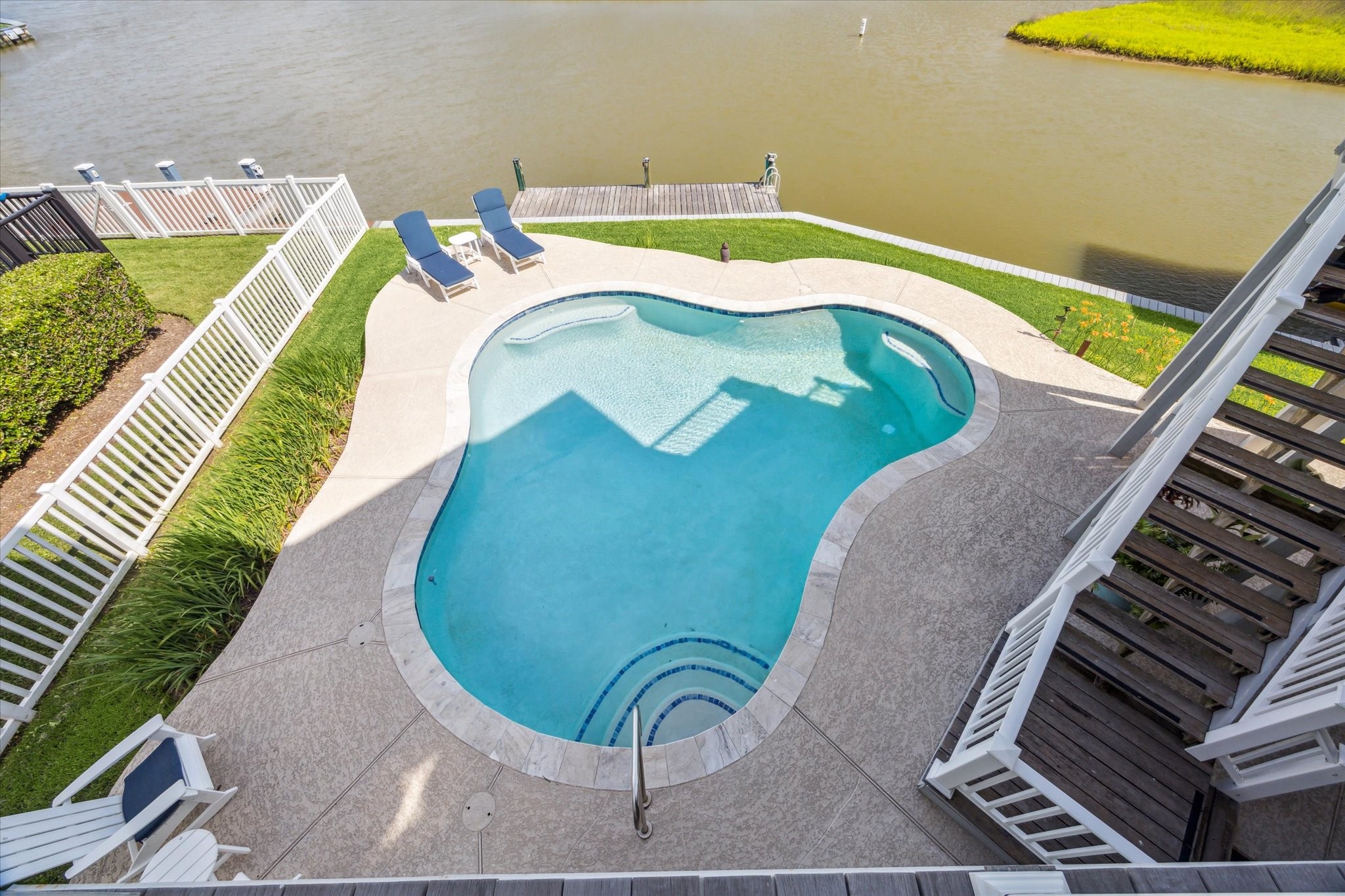1 Shell Key Hitchcock, TX 77563 - Photo 48 of 50 This aerial view showcases a beautifully designed, swimming pool set along a waterfront backdrop. The pool is surrounded by a spacious deck with ample room for lounging