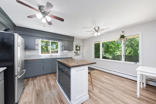 a kitchen with granite countertop a stove a sink a refrigerator and wooden floor