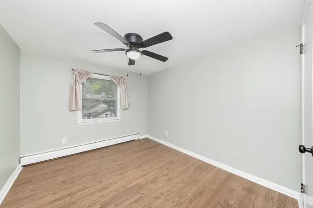 an empty room with wooden floor fan and windows
