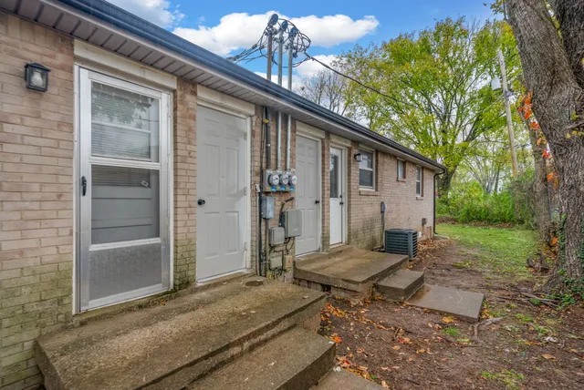 a backyard of a house with large tree and wooden fence