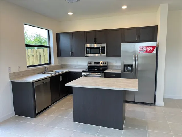 a kitchen with kitchen island granite countertop a stove top oven a sink a refrigerator and a oven