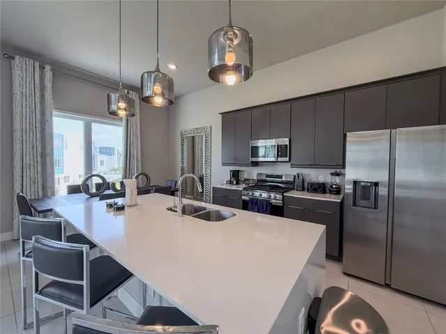a kitchen with a dining table cabinets stainless steel appliances and a chandelier