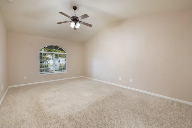 an empty room with windows and fan