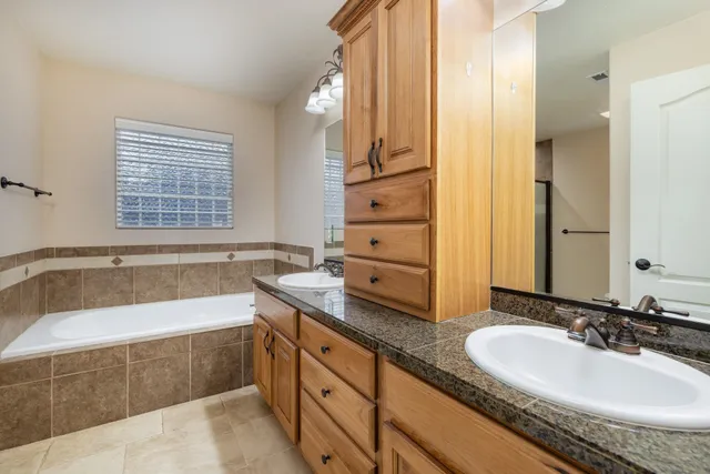 a bathroom with a granite countertop tub sink and mirror