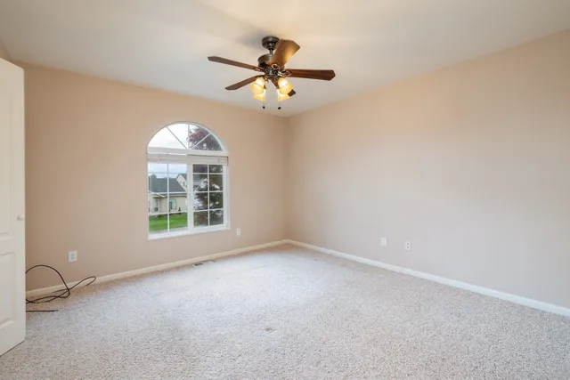 an empty room with windows and ceiling fan