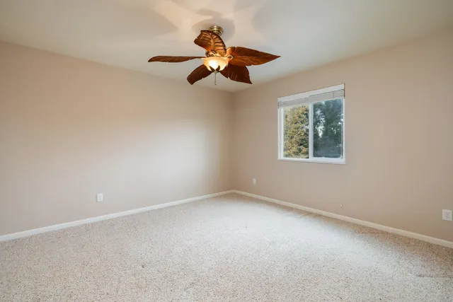 an empty room with a window and a fan