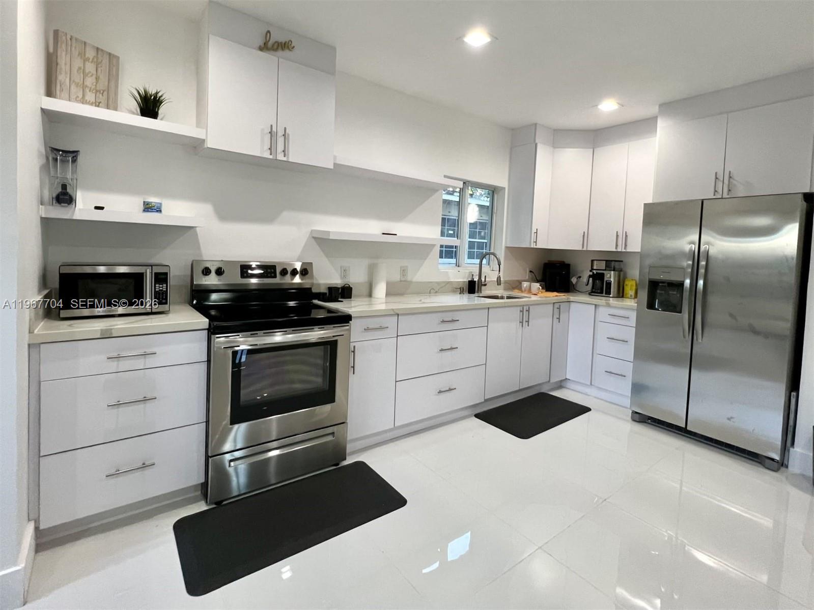1453 Northwest 70th Street Miami, FL 33147 - Photo 4 of 19 a kitchen with a stove a sink and a refrigerator
