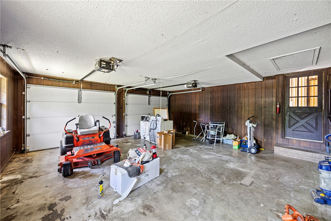 411 Marina Road Russellville, AR 72802 - Photo 39 of 49 Two-car garage featuring a concrete floor, dark wood paneling, and a pedestrian door with divided lites
