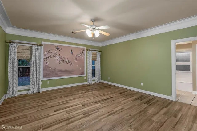 an empty room with wooden floor chandelier fan and windows