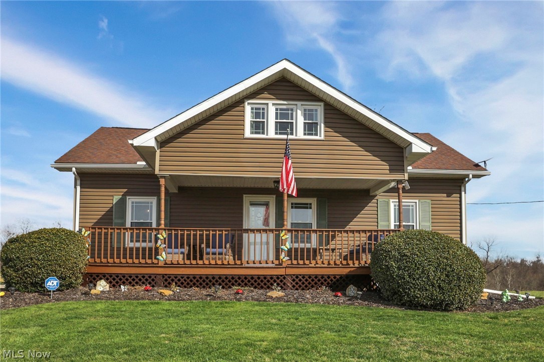 Back of property featuring a lawn and a shingled roof