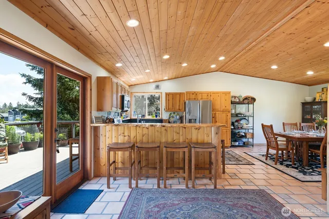 a dinning room with stainless steel appliances granite countertop a table chairs and view of kitchen
