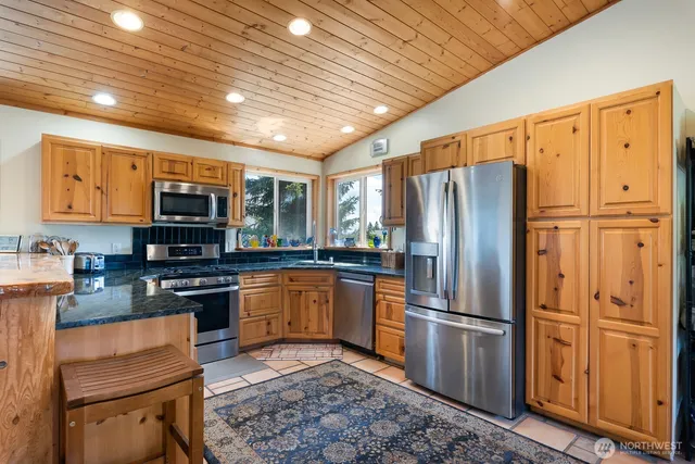 a kitchen with granite countertop stainless steel appliances a refrigerator stove top oven and sink