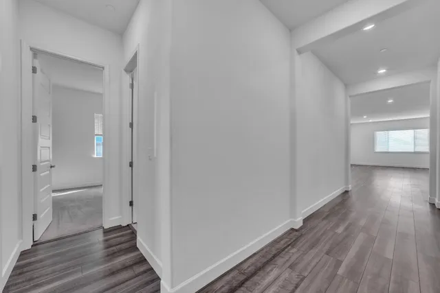 a view of a hallway with wooden floor and a bathroom