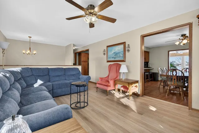 a kitchen with stainless steel appliances granite countertop a refrigerator a sink dishwasher a stove and a dining table with wooden floor