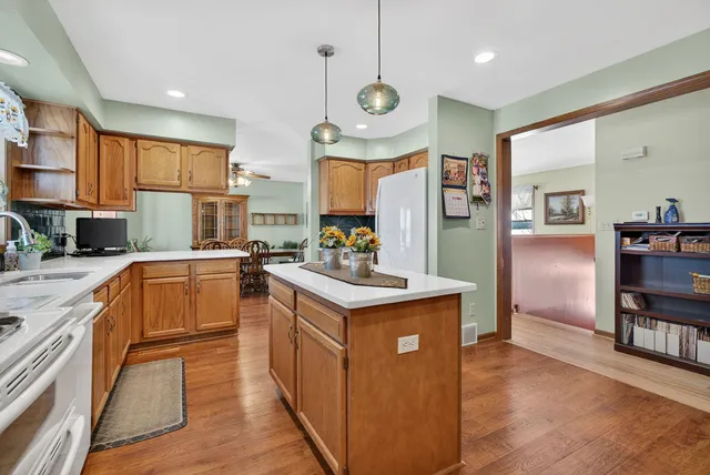 a kitchen with stainless steel appliances granite countertop a refrigerator a stove top oven a sink dishwasher and white cabinets with wooden floor