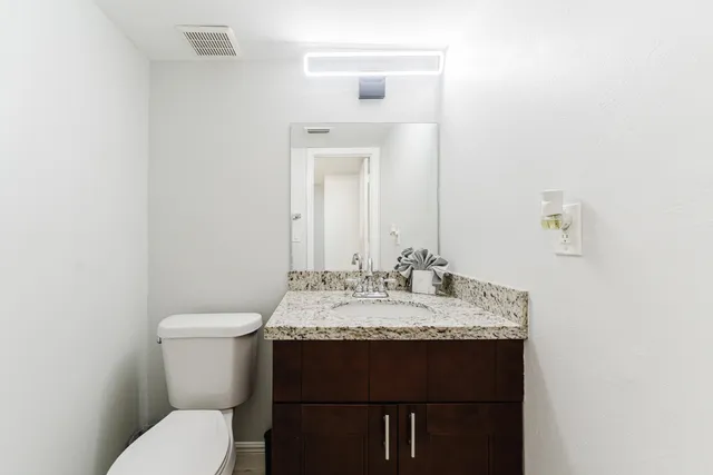 a bathroom with a granite countertop toilet sink and mirror
