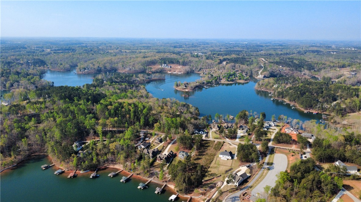 128 McAlister Road West Union, SC 29696 - Photo 30 of 40 An aerial panorama reveals a vast, serene lake bordered by a vibrant green forest and numerous homes, each with private boat docks.